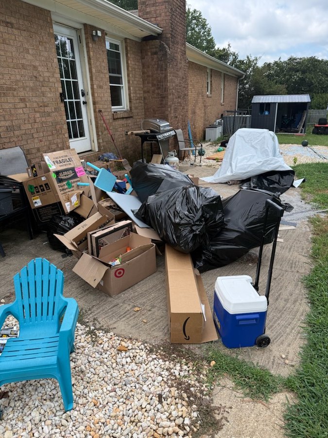 Back patio in Spartanburg SC piled with black trash bags, flattened cardboard boxes and unwanted furniture before junk removal
